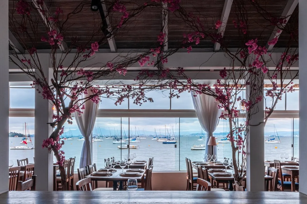 Restaurante Amalfi em Paraty decorado com flores e vista para o mar com veleiros ao fundo