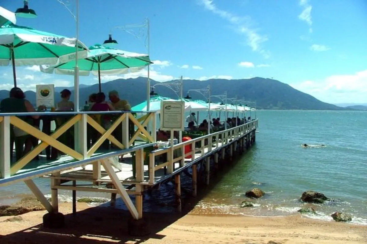 Mesas ao ar livre sobre deck do restaurante Ostradamus em Florianópolis com vista para o mar