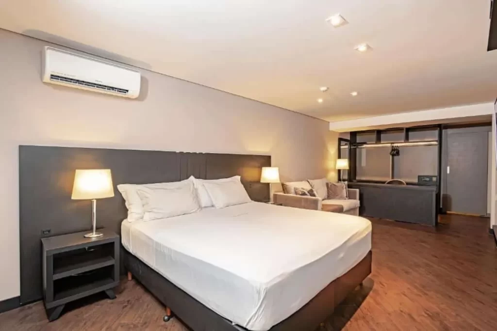 Quarto de hotel moderno em Florianópolis com cama king-size e ar condicionado, ideal para viajantes perto do aeroporto.