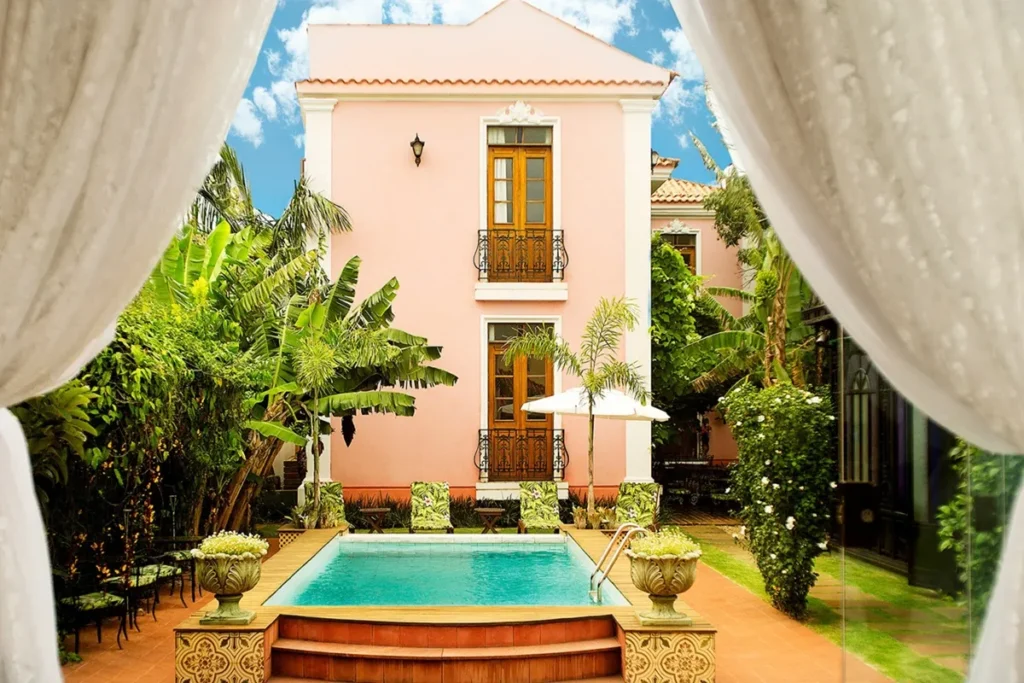 Hotel boutique rosa na Lagoa da Conceição em Florianópolis com piscina ao ar livre, jardim tropical e arquitetura elegante.