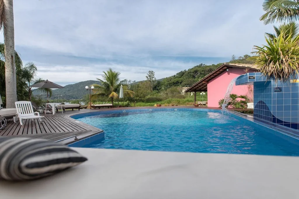 Piscina de hotel na Lagoa da Conceição em Florianópolis com vista para montanhas, área de lazer e ambiente tropical.