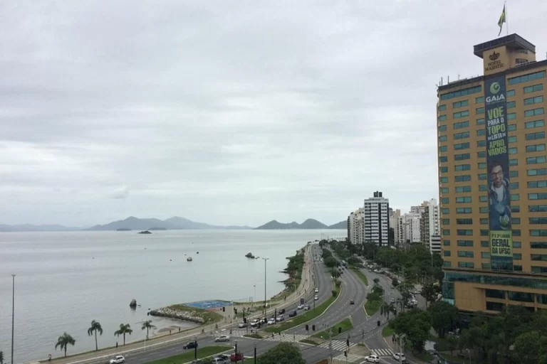 Vista panorâmica da Beira-Mar Norte em Florianópolis, com a avenida, edifícios e o mar calmo sob um céu nublado, um dos principais pontos turísticos do que fazer em Floripa.