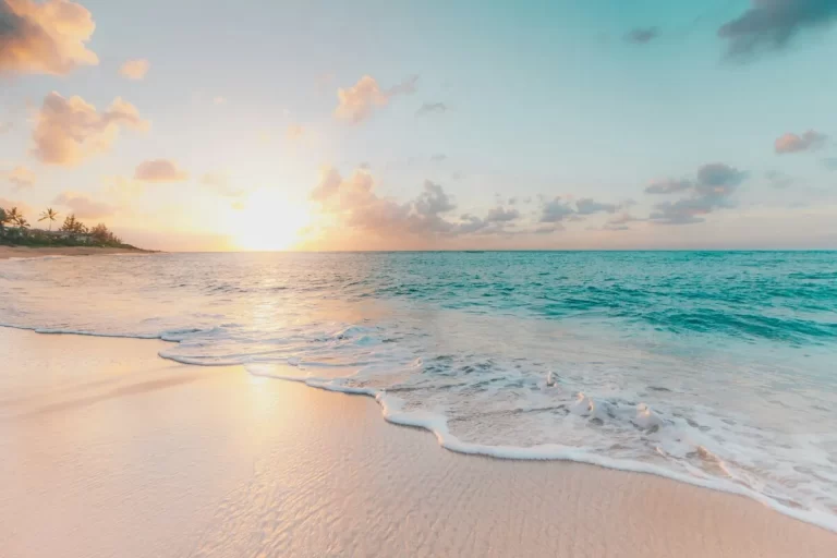 Nascer ou pôr do sol suave na Praia da Joaquina, com o sol refletindo na areia clara e ondas turquesa, criando uma atmosfera tranquila e convidativa em Florianópolis.