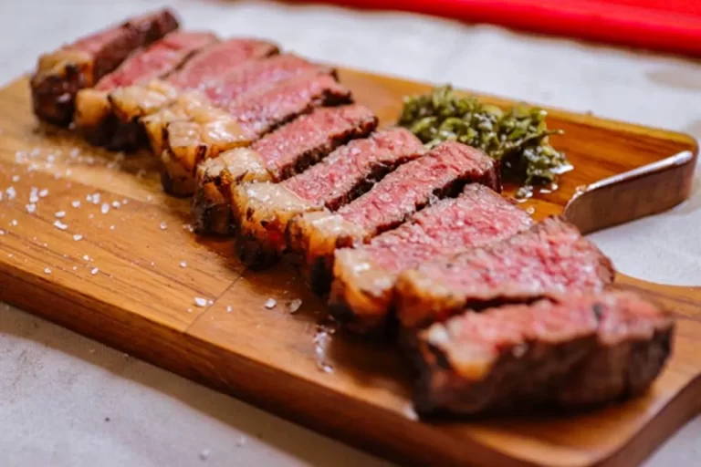 Cortes de picanha grelhada fatiada ao ponto, servidos em tábua de madeira com molho chimichurri e sal, prato de churrascarias em Florianópolis.