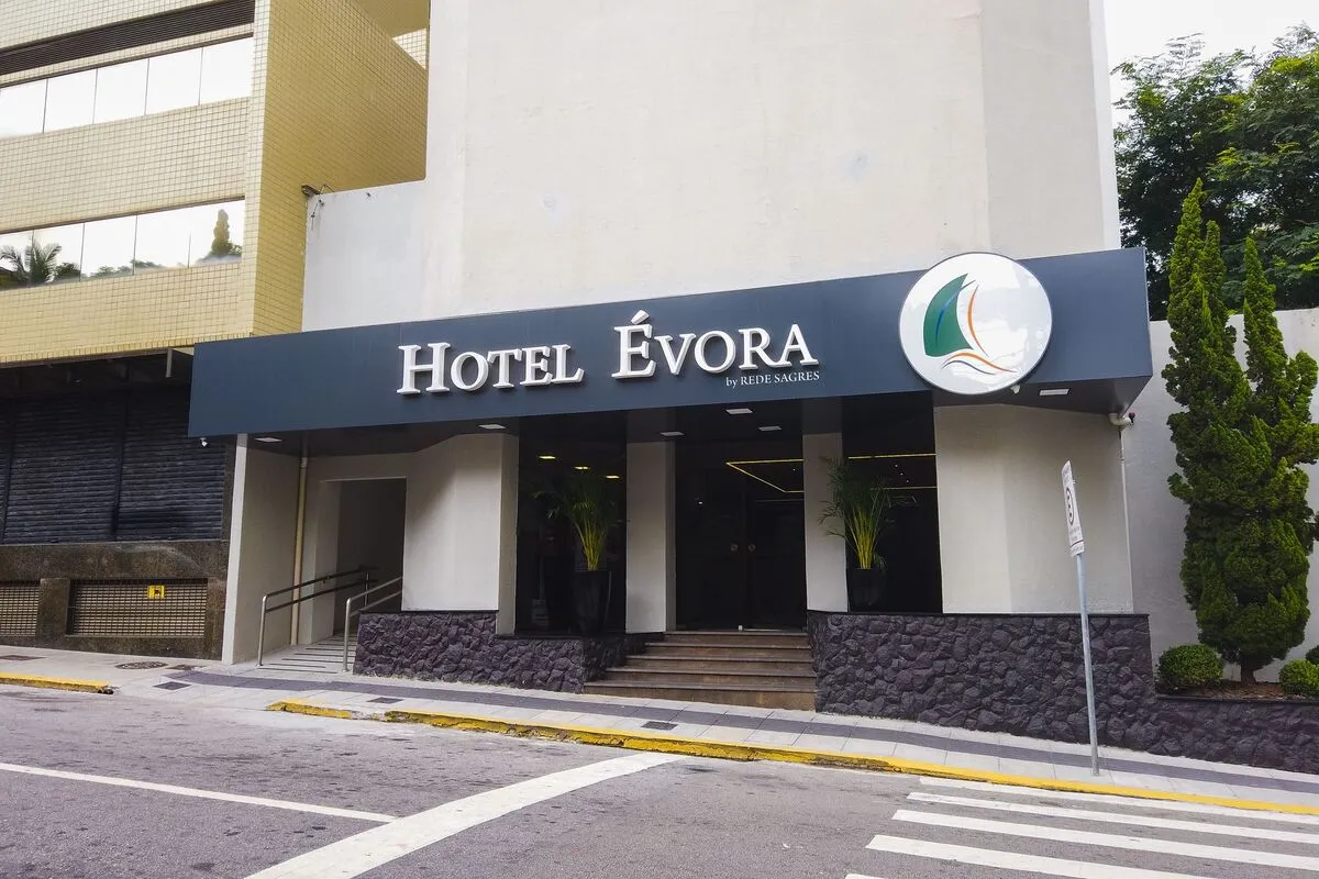 Entrada principal do Hotel Évora em Belo Horizonte, com fachada moderna, rampa de acessibilidade e letreiro da Rede Sagres.