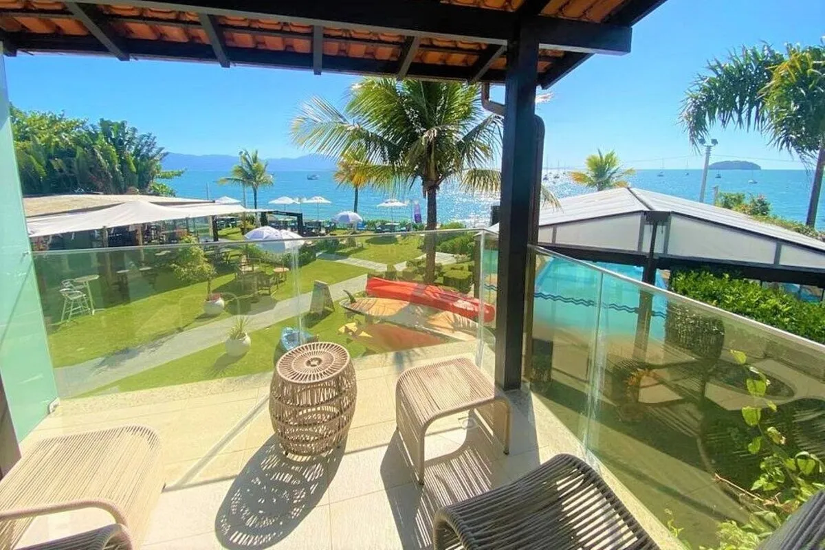 Varanda de suíte no Hotel Sete Ilhas em Florianópolis com vista para o mar e jardim com coqueiros.