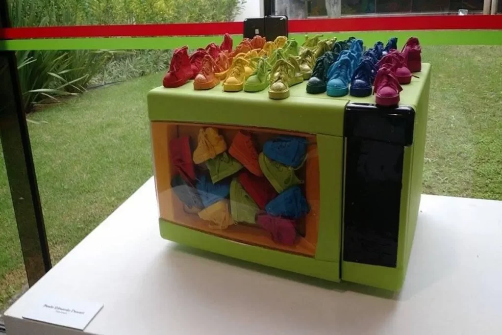 Obra de arte contemporânea no Museu de Arte de Santa Catarina: micro-ondas verde repleto de mini tênis coloridos, explorando criatividade e crítica cultural.