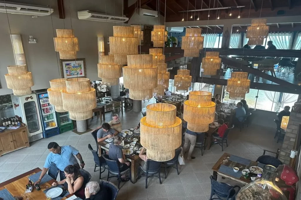 Vista do salão interno do Rancho Açoriano, restaurante de frutos do mar com decoração aconchegante e luminárias artesanais.
