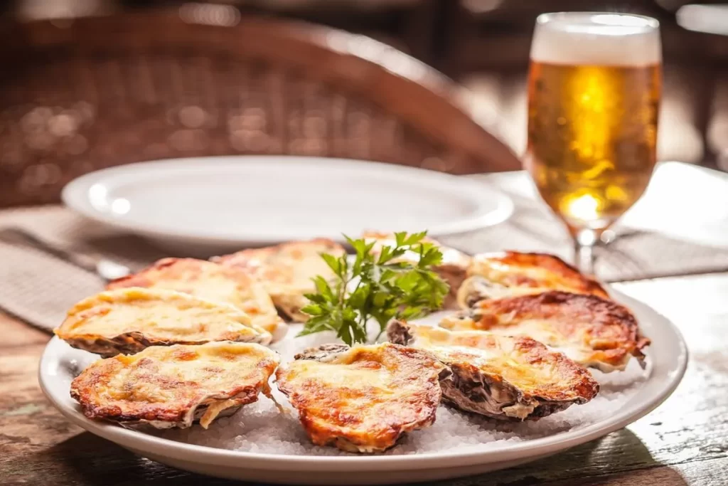 Prato de ostras gratinadas servido no Rancho Açoriano, acompanhado de cerveja gelada.