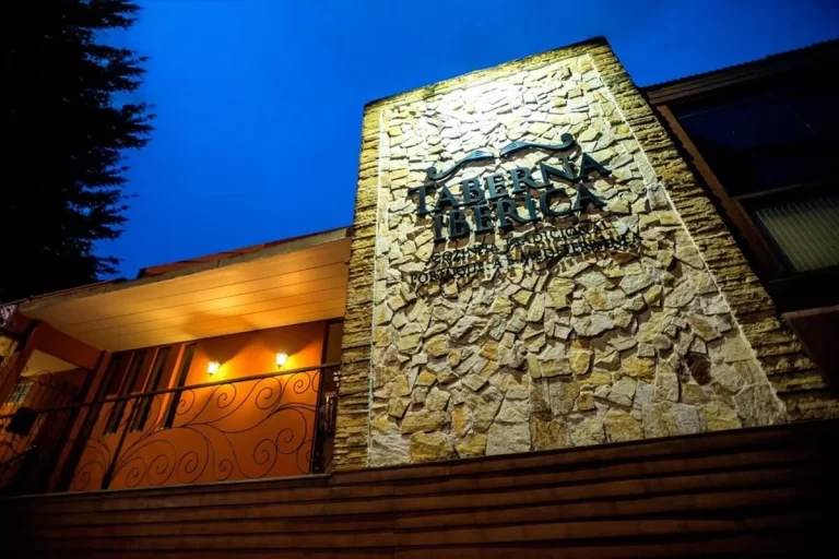 Entrada da Taberna Ibérica em Florianópolis com fachada de pedra iluminada à noite.