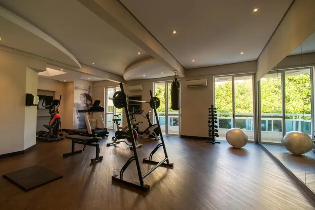 Academia interna moderna com esteira, bicicleta ergométrica, pesos e espaço fitness iluminado