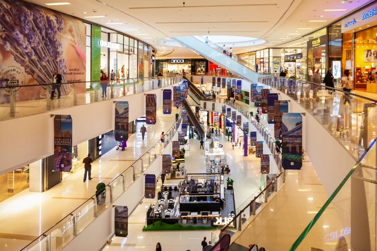 Área interna de shopping com corredores amplos, lojas iluminadas e pessoas circulando pelos andares.