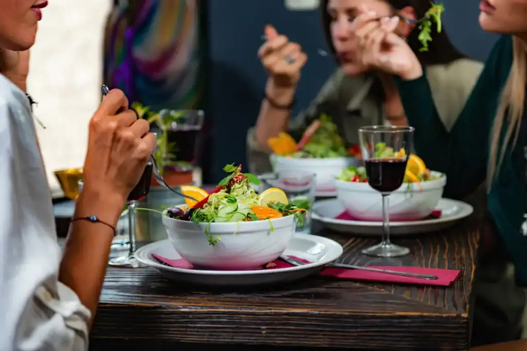 Restaurantes açorianos Florianópolis. Garçom atendendo clientes sentados em mesa de restaurante enquanto entrega o cardápio.