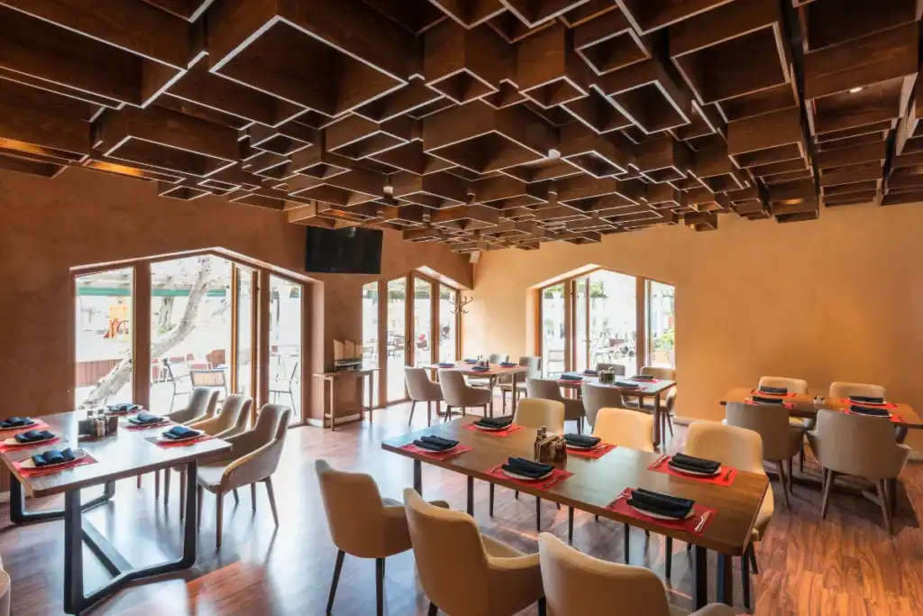 salão interno de restaurante com mesas organizadas, cadeiras estofadas e iluminação moderna