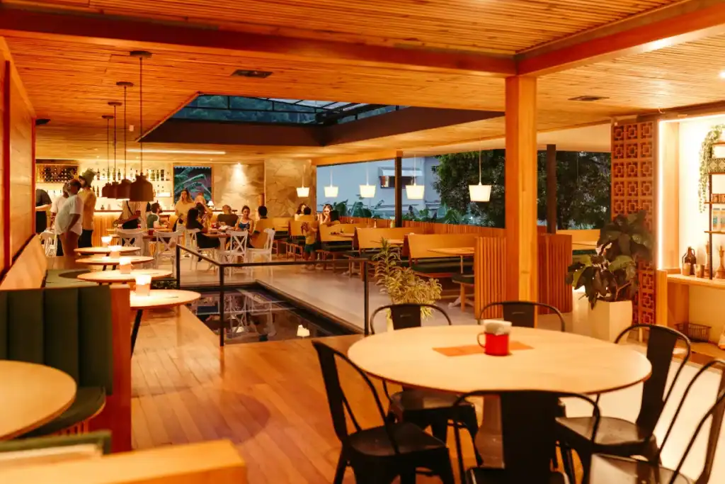 Restaurantes baratos Florianópolis. Restaurante aconchegante com iluminação quente e mesas ocupadas por clientes