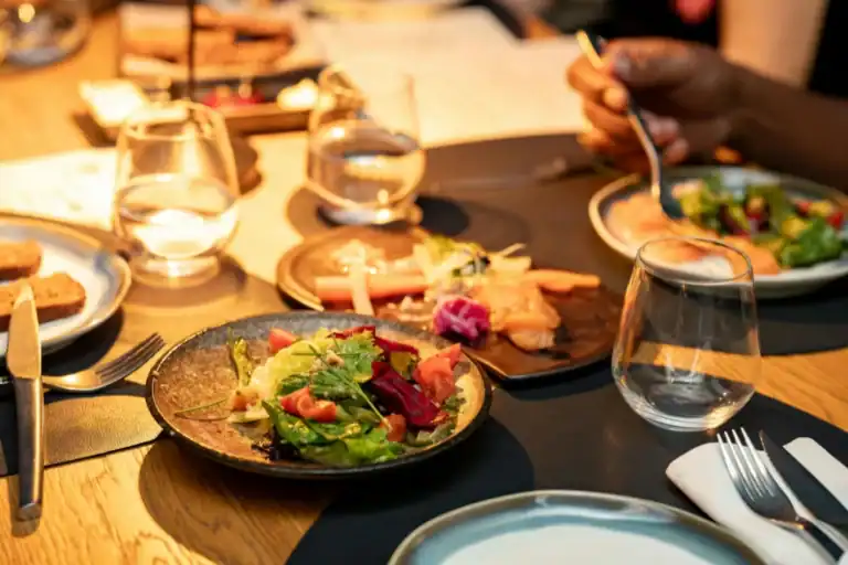 mesa com pratos variados incluindo salada colorida e pequenas porções em ambiente de restaurante