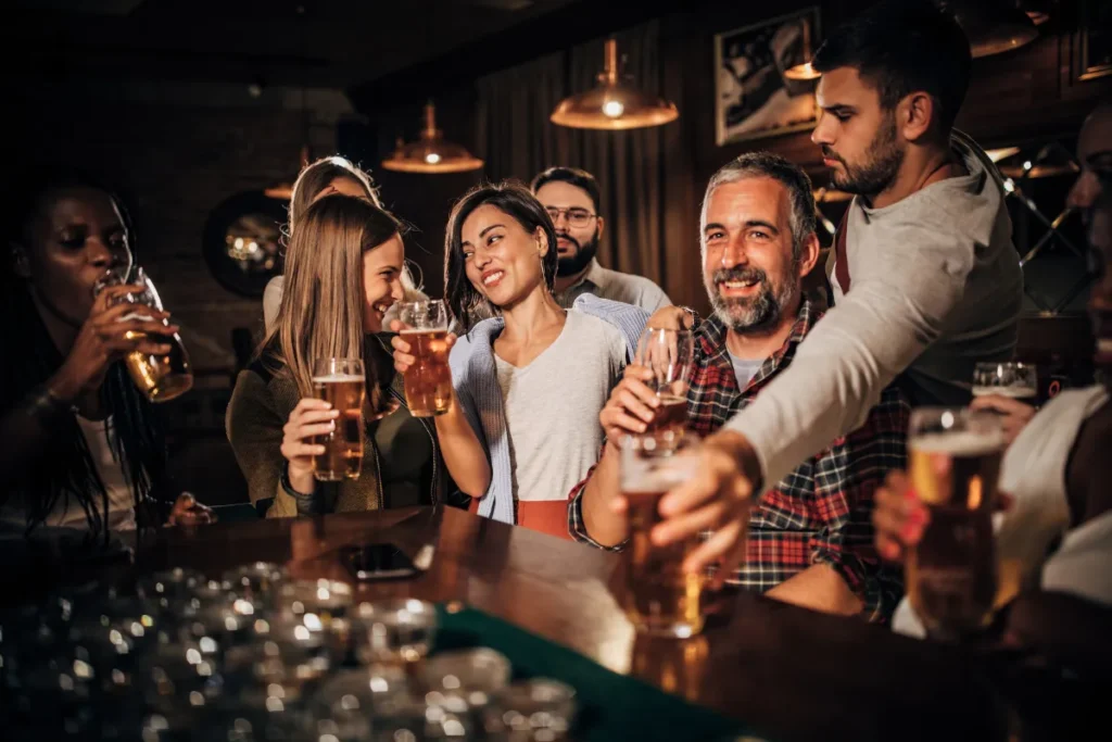 Bares na Lagoa da Conceição. Grupo de pessoas brindando com copos de cerveja em um bar com iluminação aconchegante