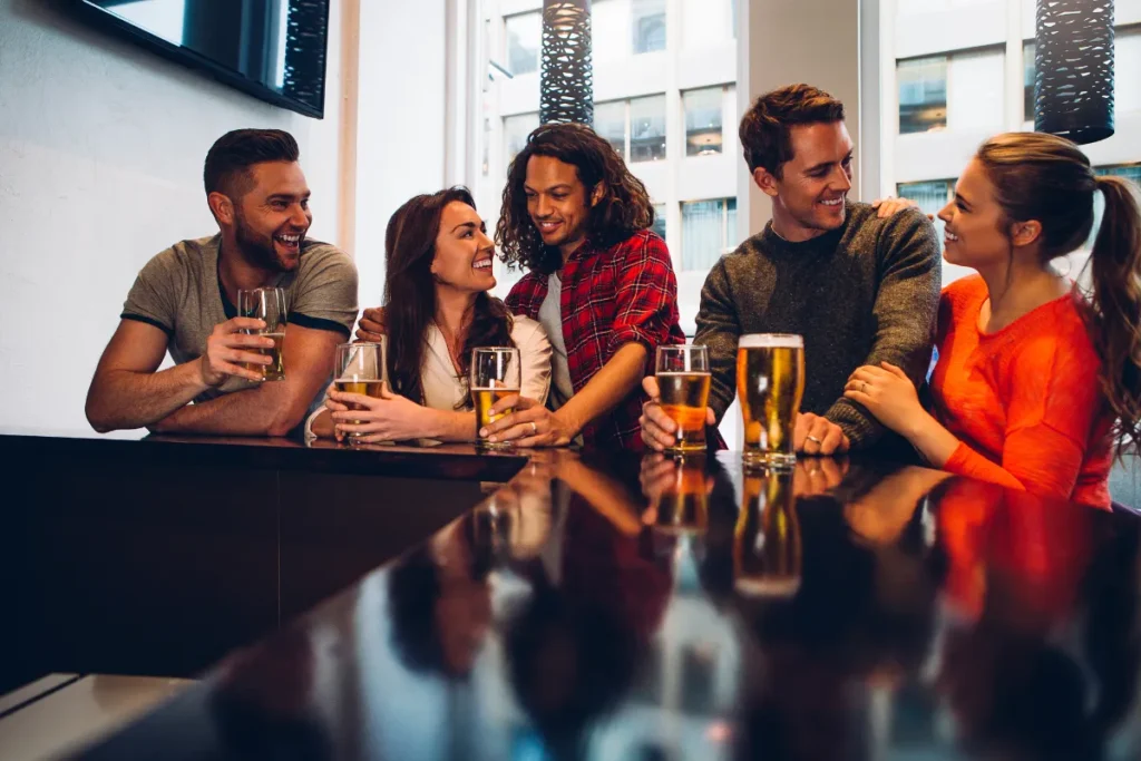 grupo de amigos conversando e brindando com copos de cerveja em um bar moderno
