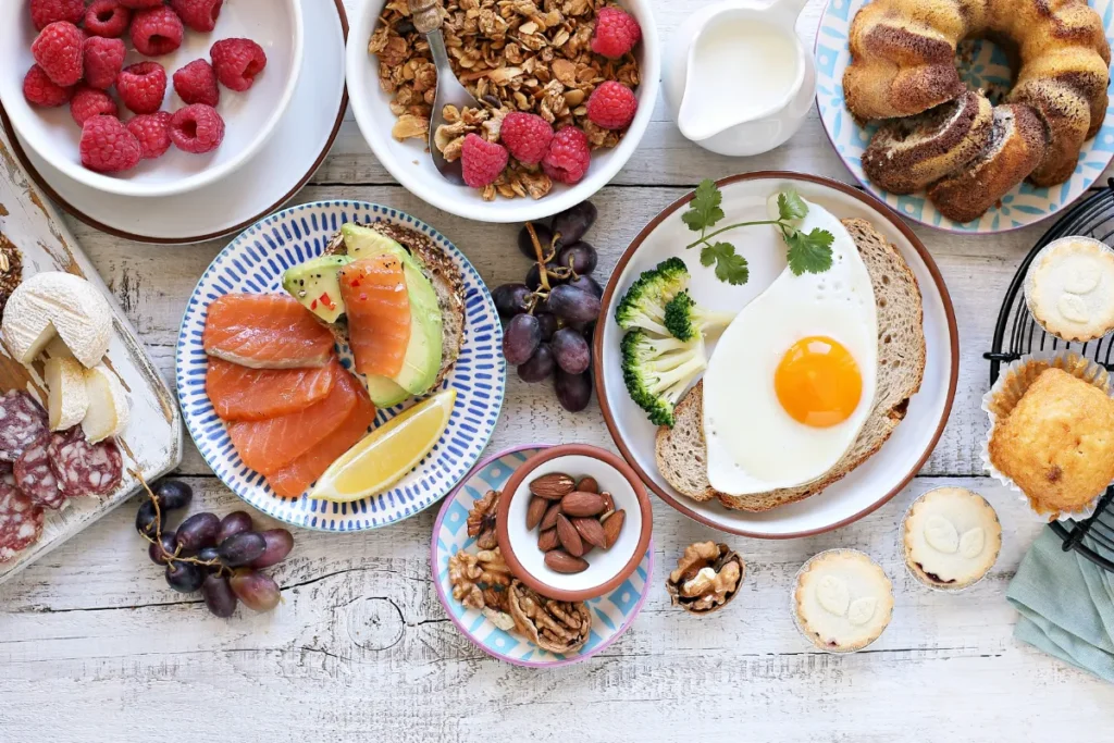 mesa com alimentos de brunch como ovo, salmão, frutas, granola e pães
