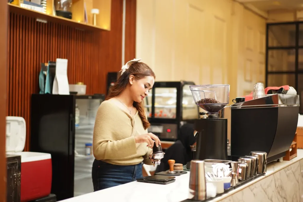 barista preparando café em máquina profissional com grãos moídos em balcão de cafeteria