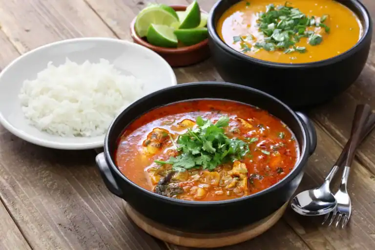 Prato com caldo de frutos do mar servido em tigela, acompanhado de arroz branco e limão