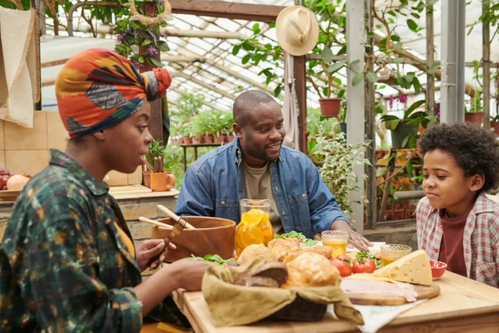 Família reunida à mesa compartilhando alimentos e bebidas em ambiente com plantas