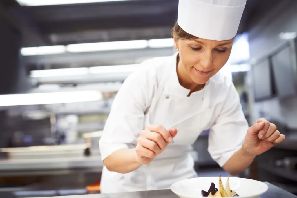 Chef finalizando prato com decoração delicada em cozinha profissional
