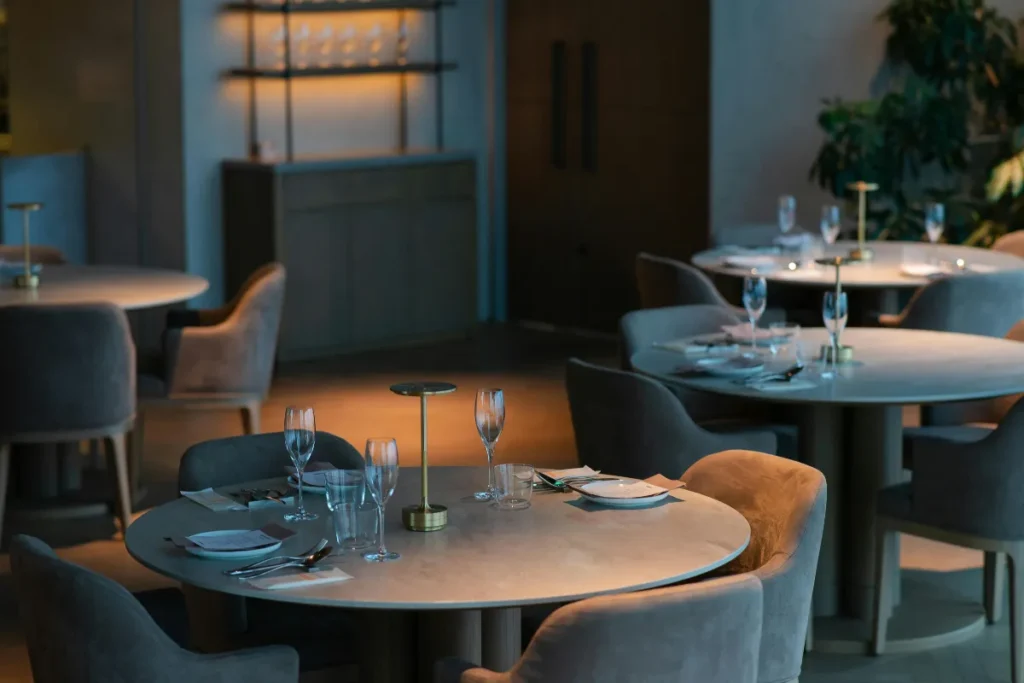 mesas redondas em restaurante moderno com iluminação suave e cadeiras estofadas em ambiente elegante
