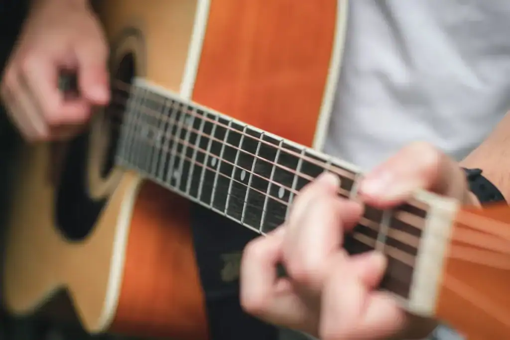 Restaurantes com música ao vivo Florianópolis. Mãos tocando violão acústico com foco nas cordas e nos dedos durante uma apresentação