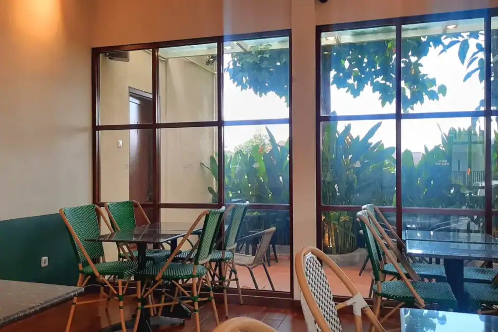 mesas de restaurante próximas a janelas de vidro com vista para jardim externo