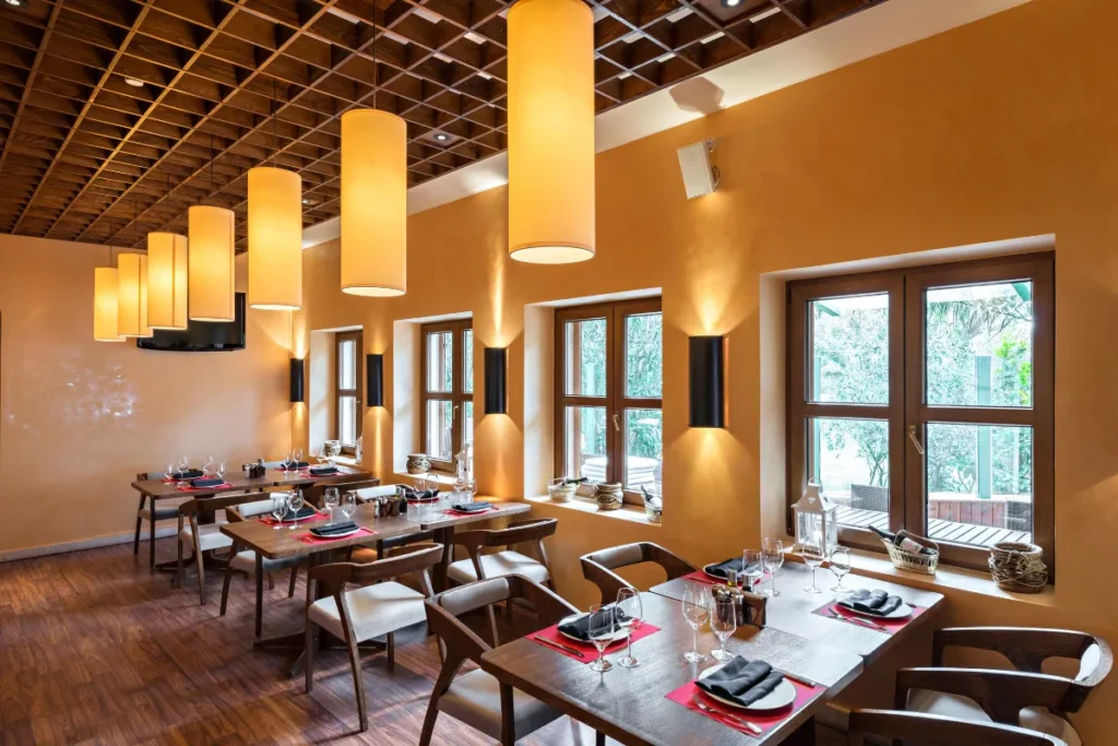 Restaurantes em Jurerê. Restaurante com mesas postas, janelas grandes e luminárias pendentes em ambiente elegante