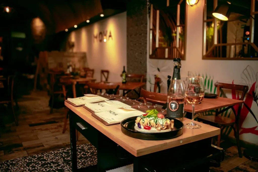 Restaurantes em Santo Antônio de Lisboa. Mesa de restaurante com prato servido, taça de vinho e garrafa em ambiente intimista em Florianópolis