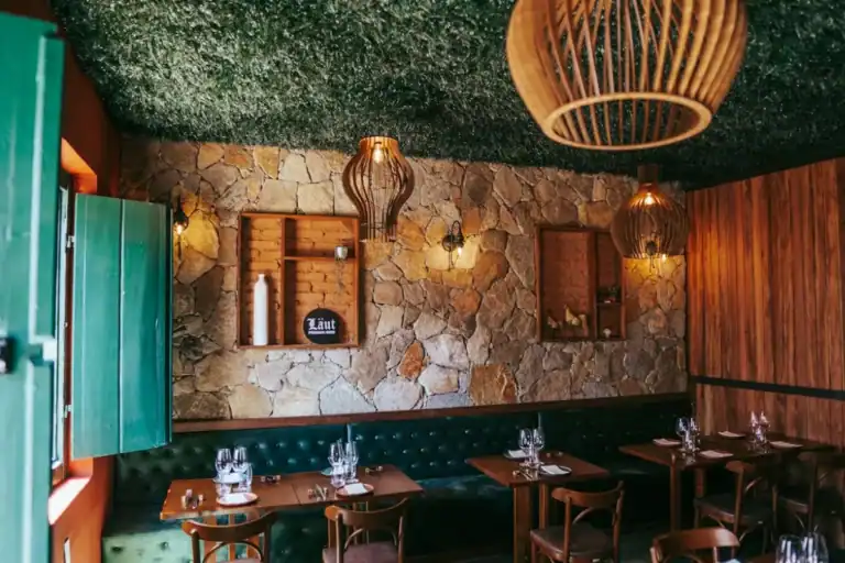 Interior de restaurante aconchegante com paredes de pedra, mesas de madeira e iluminação quente em Santo Antônio de Lisboa
