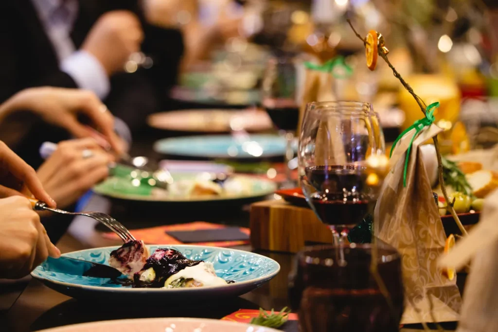 pessoa comendo prato com molho escuro em restaurante com taça de vinho na mesa