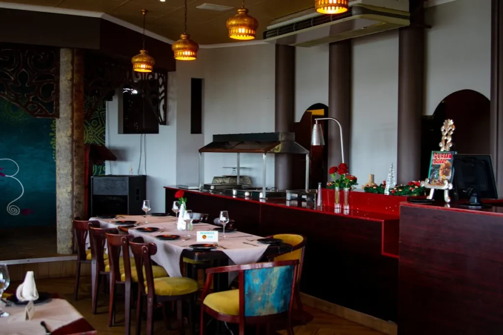 Restaurantes no Campeche. Interior de restaurante com iluminação quente, mesas arrumadas e balcão ao fundo no Campeche em Florianópolis