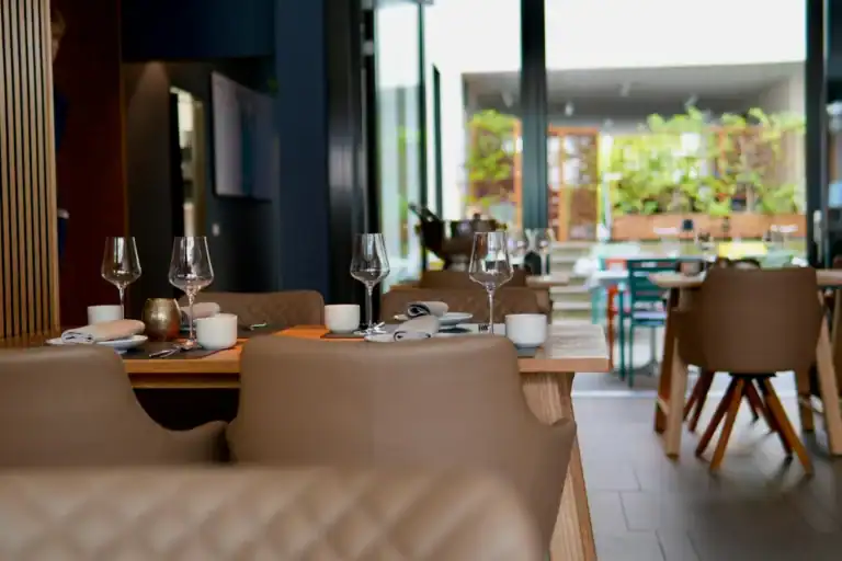 mesa posta em restaurante sofisticado com taças de vinho e cadeiras acolchoadas em ambiente moderno e iluminado