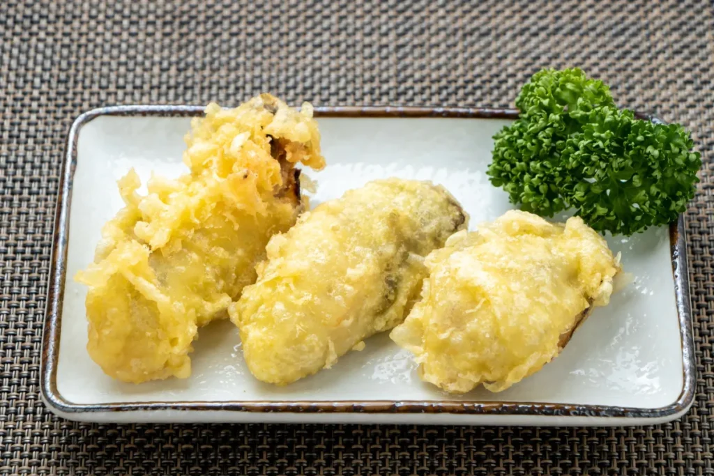 Rota das ostras Florianópolis. Ostras empanadas servidas em prato com acompanhamento de ervas