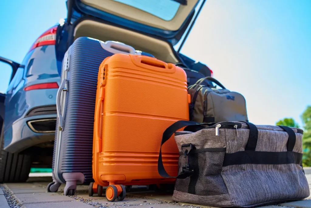 malas e bolsas organizadas no porta malas de carro aberto, representando preparacao para viagem entre Florianopolis e Porto Alegre