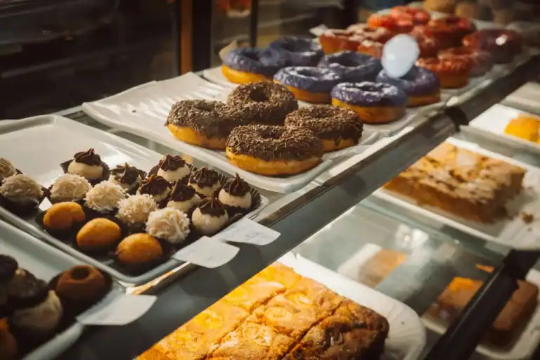 vitrine de confeitaria com donuts coloridos, brigadeiros e outros doces expostos