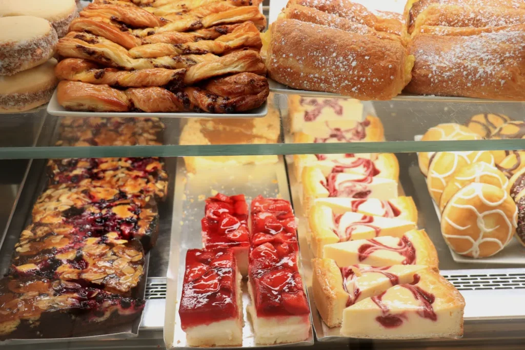vitrine com bolos em fatias, tortas e pães doces organizados em prateleiras