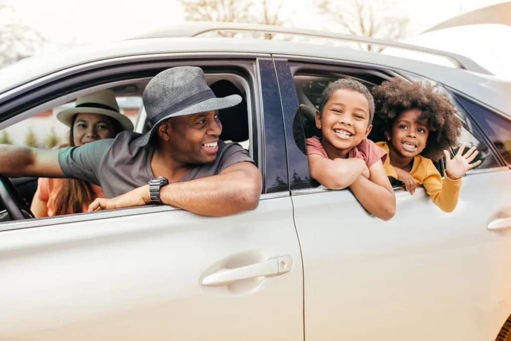 Família sorrindo dentro de carro durante viagem, representando deslocamento rodoviário entre Florianópolis e cidades do interior de Santa Catarina