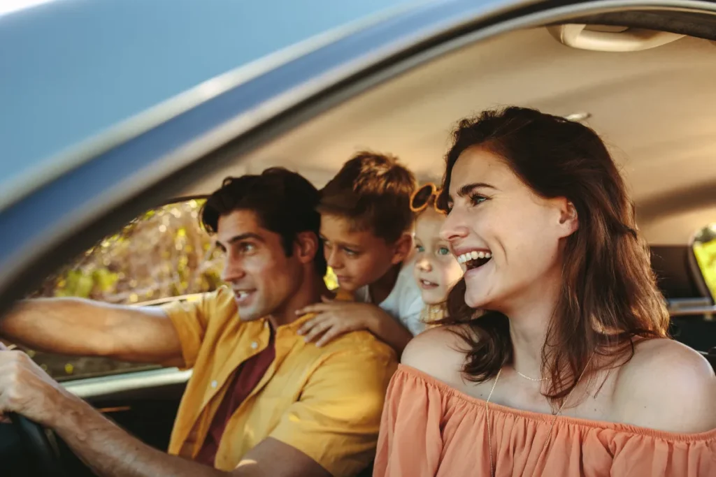 família dentro do carro sorrindo durante viagem, representando deslocamento entre Florianópolis e Curitiba com crianças