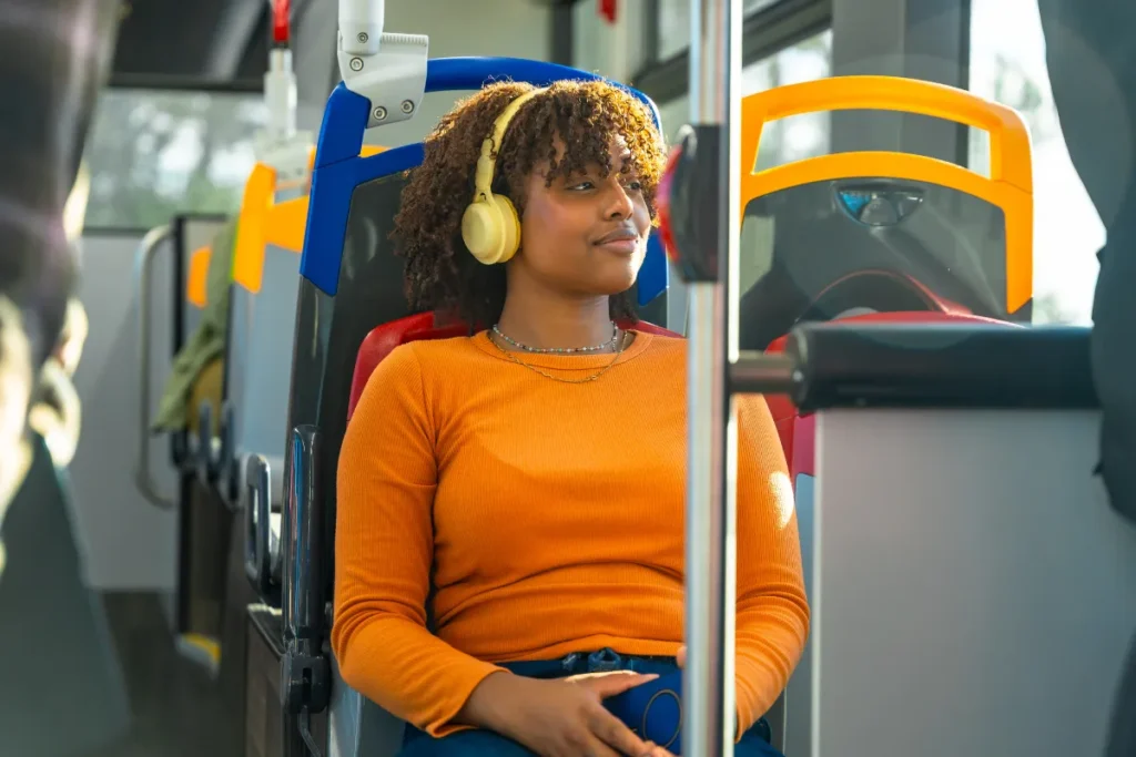 Passageira sentada em ônibus usando fones de ouvido, mostrando conforto durante viagem entre Florianópolis e Joinville