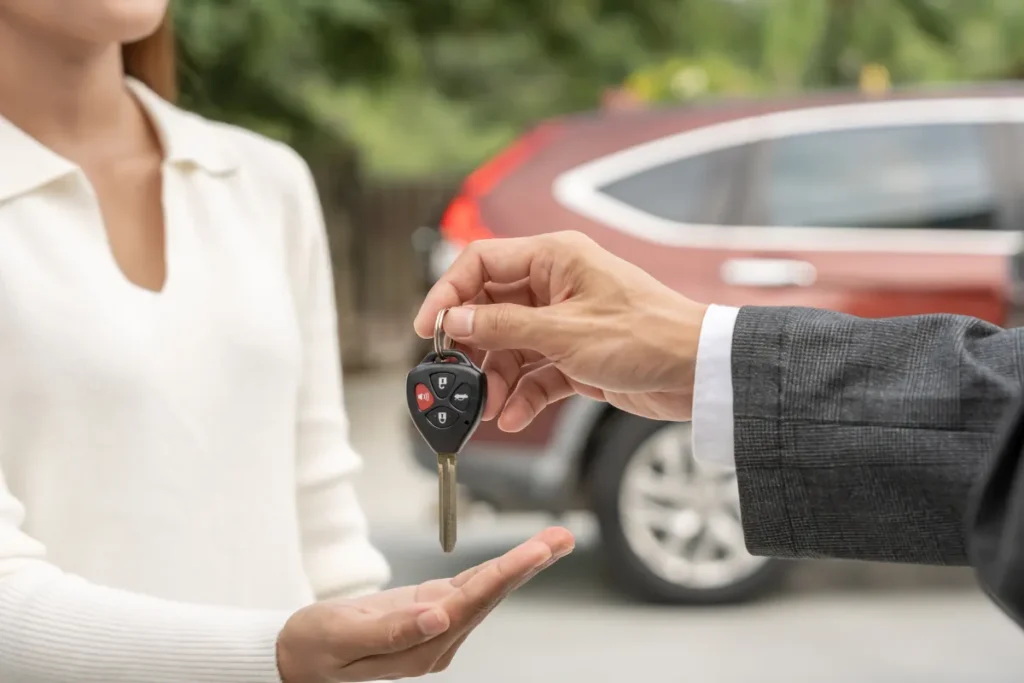 Cliente recebendo chave de carro de atendente ao lado de veículo, situação comum ao alugar carro em Florianópolis