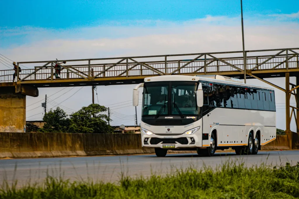 Ônibus circulando em via urbana com passarela ao fundo, representando o sistema de transporte público em Florianópolis