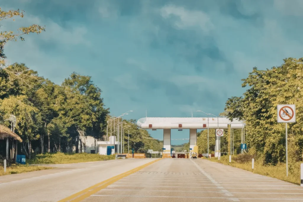 Rodovia com acesso a pedágio ao fundo cercado por vegetação, ilustrando entrada em praça de cobrança na BR-101 em Santa Catarina