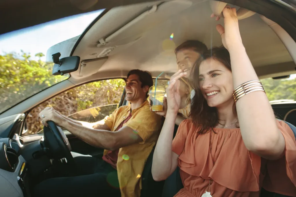 casal sorrindo dentro de carro durante road trip com luz natural, ilustrando deslocamento de Florianópolis para Curitiba de forma confortável