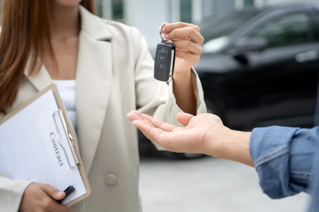 Pessoa recebendo chave de carro enquanto segura prancheta com contrato, típico de retirada de veículo alugado