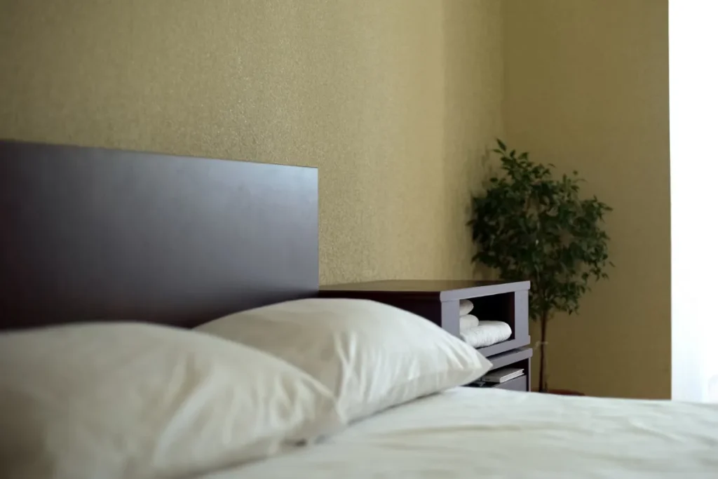 Cama de hospedagem simples com travesseiros e ambiente minimalista em hotel barato de Florianópolis