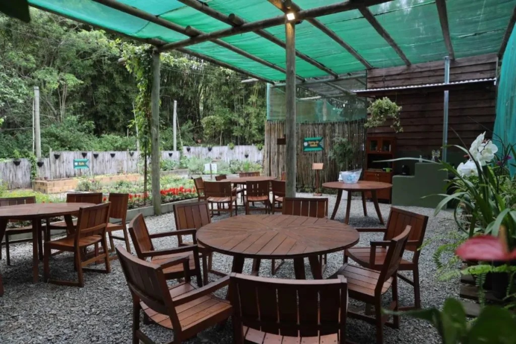 Área externa tranquila com mesas e natureza ao redor no Costão do Santinho em Florianópolis.